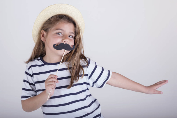 Beautiful cute little girl playing with mustache - Photo, Image