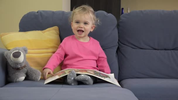 Suloinen tyttö luki kirjaa sohvalla huoneessa. Koulutus, lapsuus. 4K
 - Materiaali, video