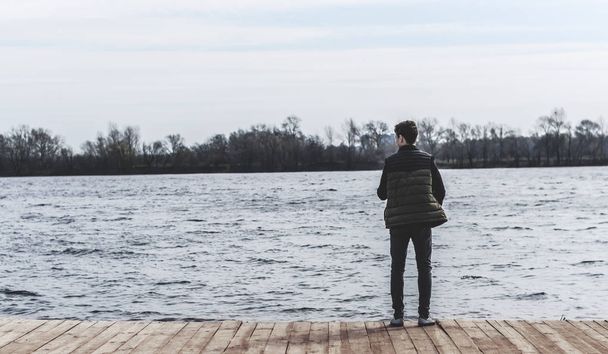 teenager, stojící na okraji mola nedaleko vody - Fotografie, Obrázek