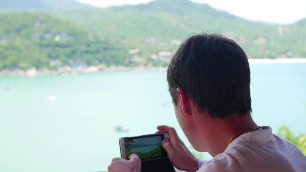 Der Fotograf fotografiert mit seinem Smartphone das Meer und die Berge von einem anderen Standpunkt aus. Panoramablick - Filmmaterial, Video