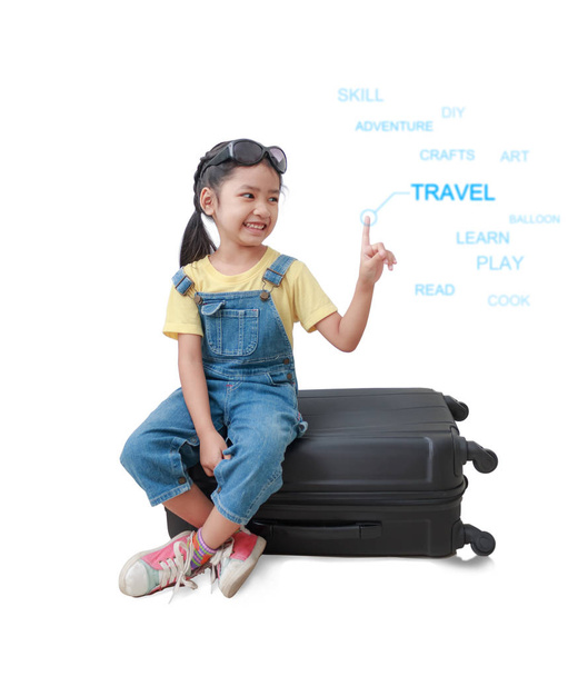Sorria menina asiática sentada na bagagem e apontando o
  - Foto, Imagem