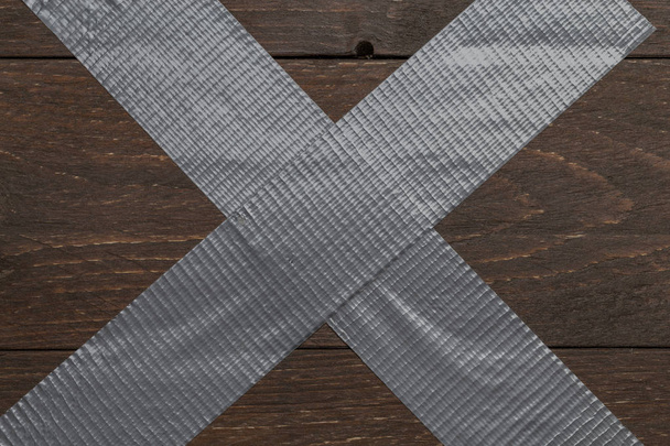 Překřížené kovové lepicí páskou na tmavém rustikální starožitné dřevěné pozadí - Fotografie, Obrázek