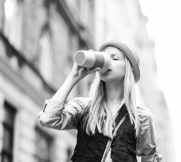 Young hipster enjoying cup of hot beverage in the city - Фото, изображение