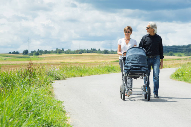 Grandparents Going For A Walk With Baby Stroller - 写真・画像