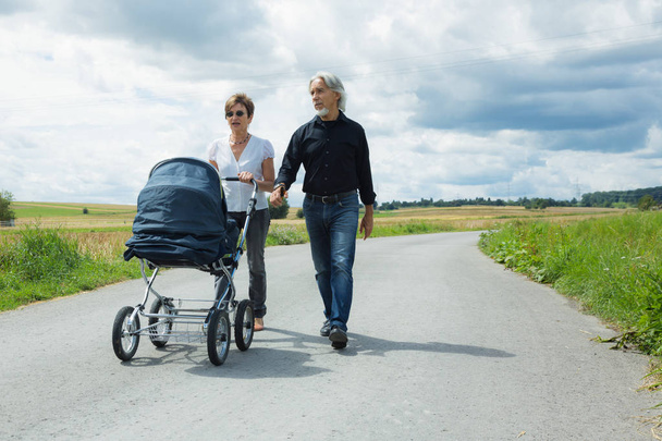 Abuelos yendo a dar un paseo con bebé cochecito
 - Foto, imagen