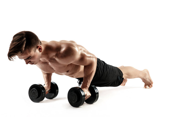 Muscular bodybuilder guy doing Push-ups on dumbbells from the floor over white background - Foto, Imagem