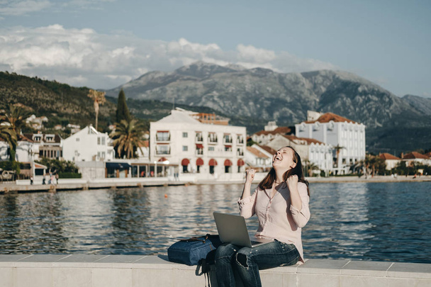 Happy Young woman sitting on Embankment with the laptop. Vacatio - Φωτογραφία, εικόνα