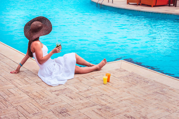 The woman enjoying cocktail in a swimming pool - Photo, Image