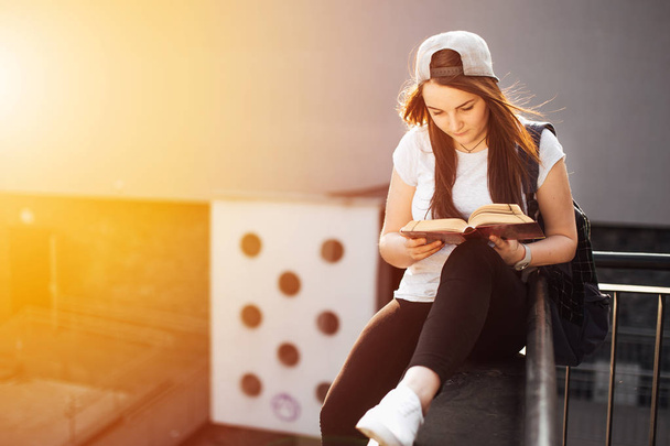 Pretty girl sit on the steps and read book with headphones - 写真・画像