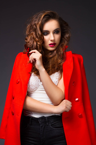 Portrait of beautiful young woman in red coat and black jeans - Fotó, kép