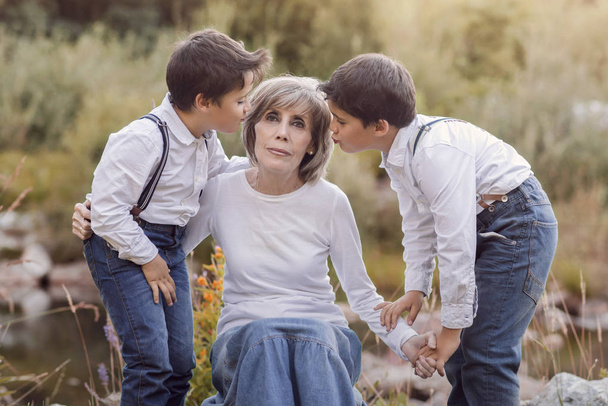 Grootmoeder met haar kleinkinderen zitten in het veld - Foto, afbeelding
