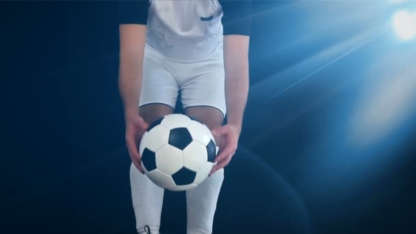Fußballer in Stiefeln, die sein Bein auf einen Ball legen, schwarzer Hintergrund - Filmmaterial, Video
