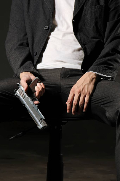 Mann mit Waffe sitzt auf Stuhl. - Foto, Bild