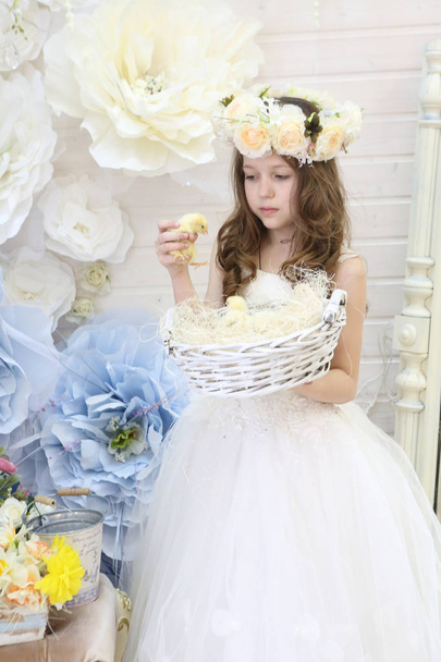 girl in a wreath and a white dress holds a woven basket with chi - Foto, Bild
