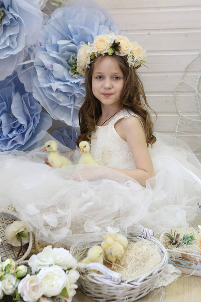 girl in a wreath and a white dress playing with a live duck - 写真・画像