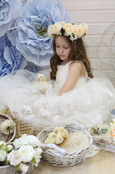 girl in a wreath and a white dress holds a live duck - Foto, Bild