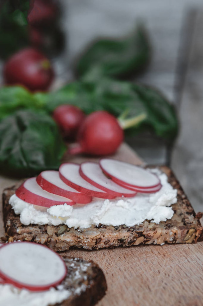 Pan de dieta con requesón, rábano y albahaca sobre madera rústica
  - Foto, imagen