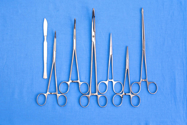 Instrumentos y herramientas quirúrgicas, incluidos bisturíes, pinzas y pinzas dispuestas en una mesa para una cirugía - Foto, imagen