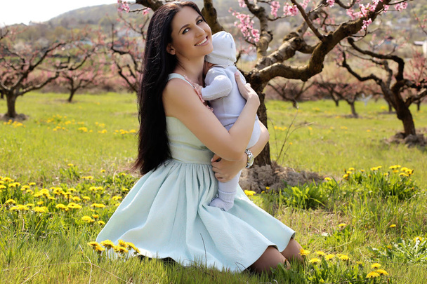 woman in elegant dress posing with her baby boy in blossom garde - Fotografie, Obrázek