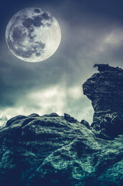 Боулдер против неба с облаками и красивой полной луной. Кросс-процесс
. - Фото, изображение