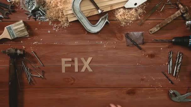 Top view time-lapse of a hand laying on wodden table words "FIX IT" - Felvétel, videó