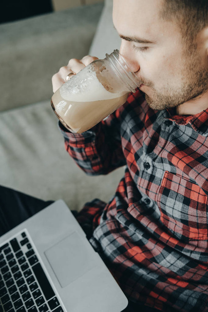 Hipster man in red checkered shirt using laptop and drinking cof - Фото, изображение