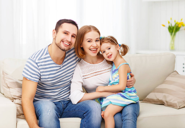 Onnellinen perhe nauraa ja halaa kotona sohvalla
 - Valokuva, kuva