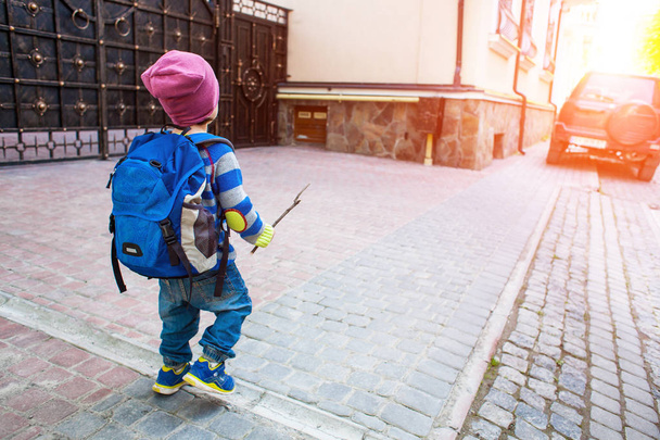 A boy with a backpack walking across the street. - Fotó, kép