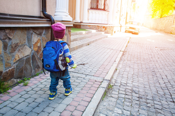 Un garçon avec un sac à dos marchant dans la rue
. - Photo, image