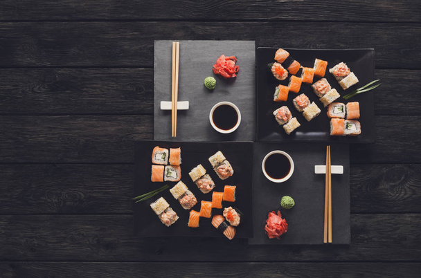 Conjunto de sushi maki e rolos em madeira rústica preta, vista superior
 - Foto, Imagem