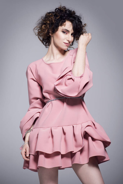 Όμορφη νεαρή γυναίκα σε ένα ροζ φόρεμα με βολάν - Φωτογραφία, εικόνα