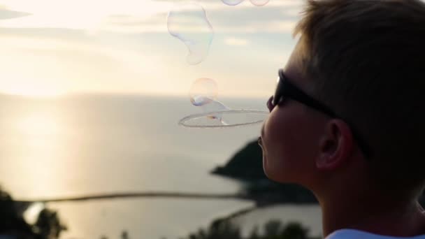 Der Junge macht Seifenblasen. Nahaufnahme. Panoramablick. Sonnenuntergang - Filmmaterial, Video