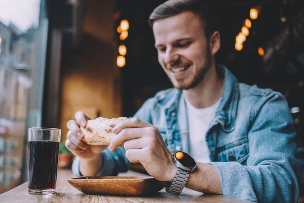 Young man sitting in a restaurant and eating a hamburger - Foto, Bild