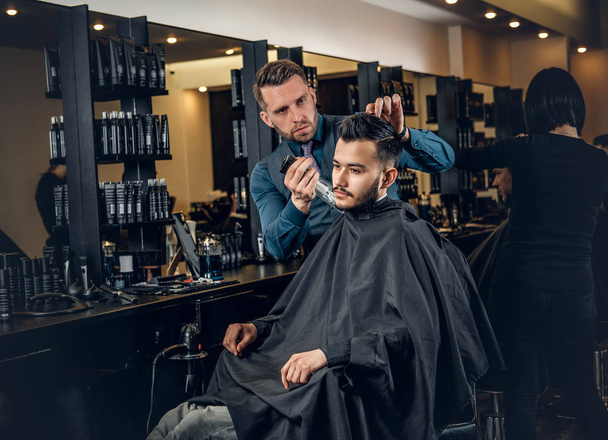 Stylish male hairdresser doing haircut  - Foto, Bild
