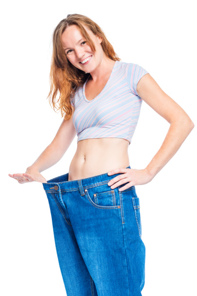 Gelukkig dunne vrouw in grote jeans glimlach tegen een witte achtergrond - Foto, afbeelding