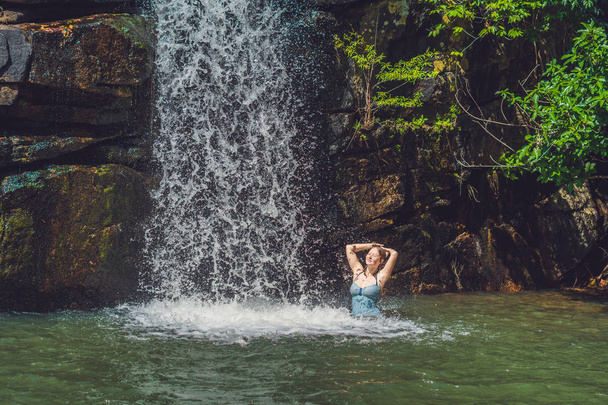 woman is standing in a waterfall - 写真・画像