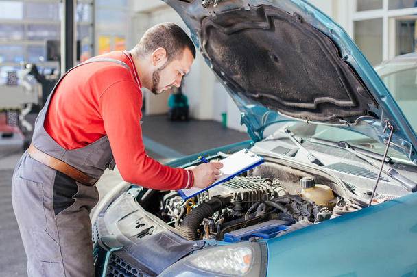 Car mechanic preparing checklist in workshop - Photo, Image
