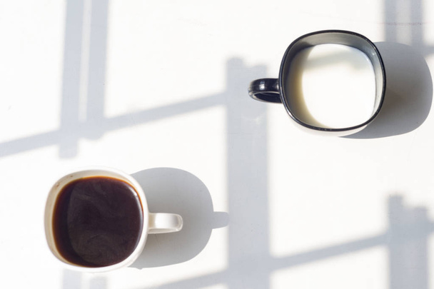 черный и белый стакан молока, кофе на естественном фоне, вид сверху
 - Фото, изображение