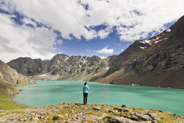 girl in blue jacket standing above blue lake with mountains surrounded - Fotó, kép