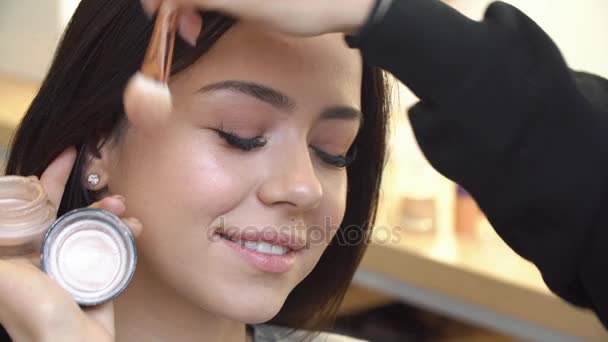 Professional make up artist applying cosmetic on face of cute teen girl for skin care and health complexion - Záběry, video