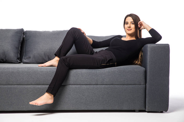 smiling young woman lying on sofa on white background - Foto, afbeelding