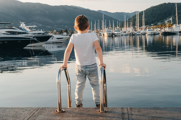 Boy playing near Yachts in port at sunset on background of sea,  - Photo, image
