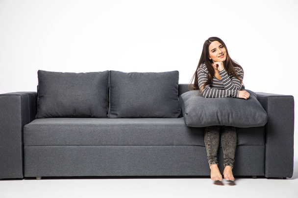 mulher sentada no sofá e abraçando um travesseiro no branco
 - Foto, Imagem