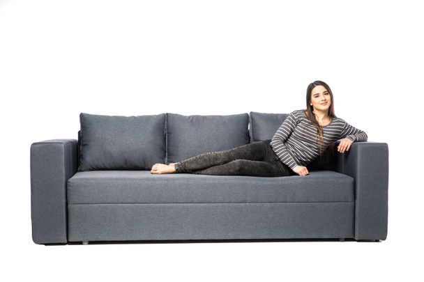 Young female lying on a sofa isolated on white background - Foto, Bild