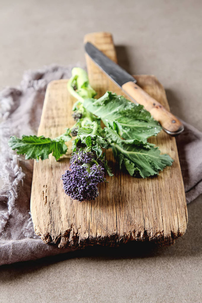 Fresh purple broccoli on a wooden plate. Vegan food. Dark backgr - Fotó, kép