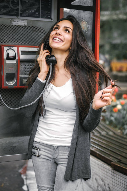 Happy and smiling woman talking in the retro phone booth - Foto, imagen