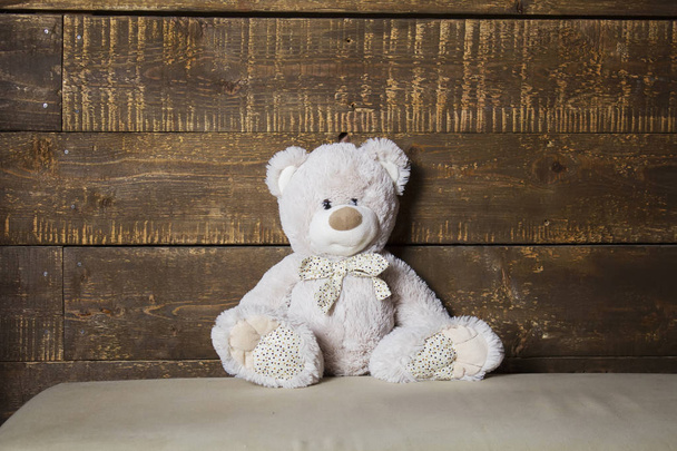 bear is sitting on the couch, plush toy - Φωτογραφία, εικόνα