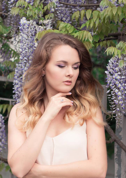 Wisteria. Portrait of a young beautiful woman near lilac flowers. Warm spring. - Foto, imagen