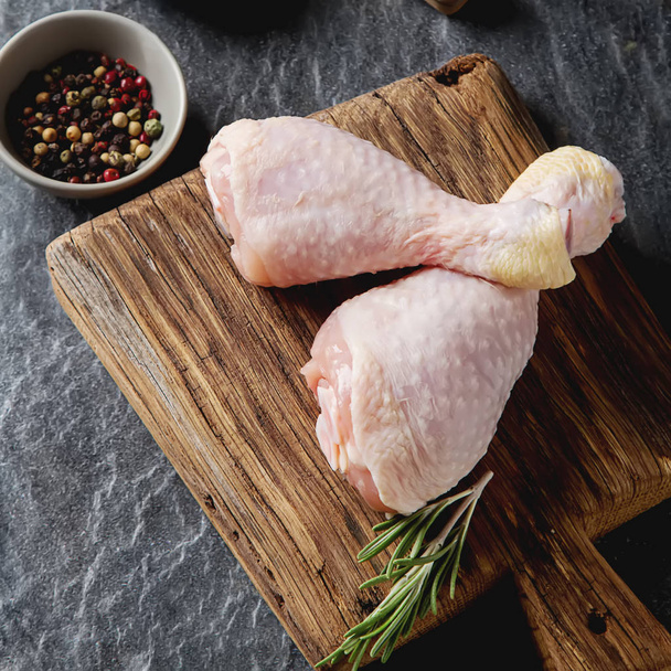 Chicken legs with rosemary and spices. Dark background. Lunch on - Photo, Image
