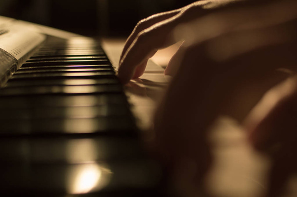 Lähikuva pehmeä keskittynyt ilmakehän kuva kädestä soittamassa pianoavaimia. Konsepti: Musiikin luominen, säveltäminen, sanoitukset, esitys
 - Valokuva, kuva